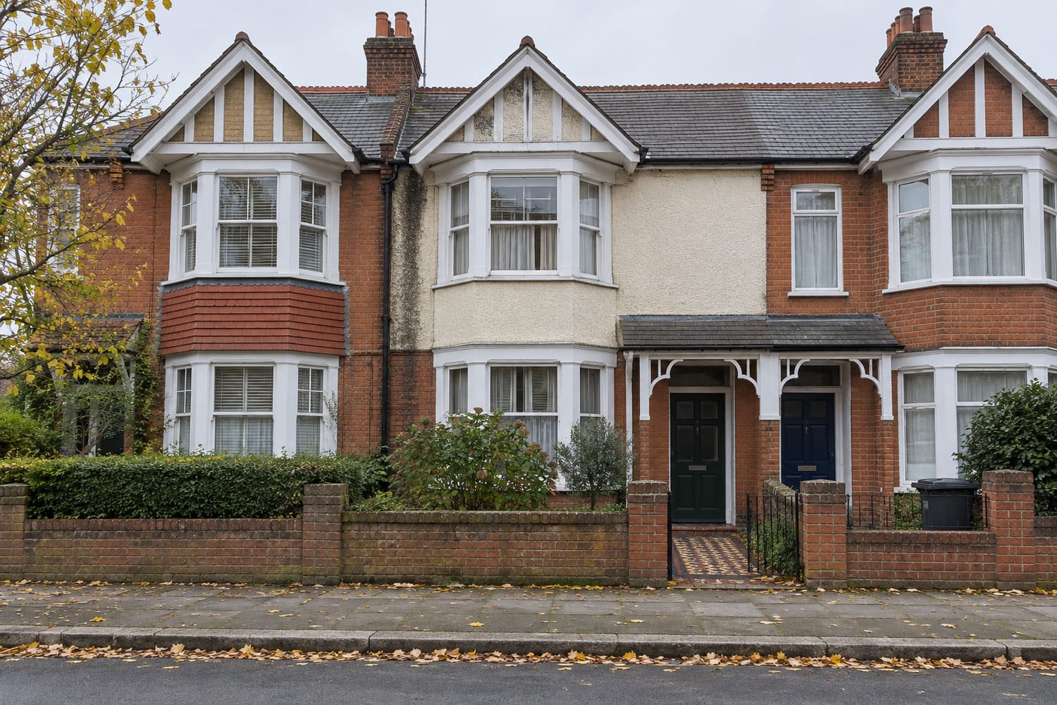 Three terraced houses with bay windows, low brick front walls and a tiled front path, seen from across the road