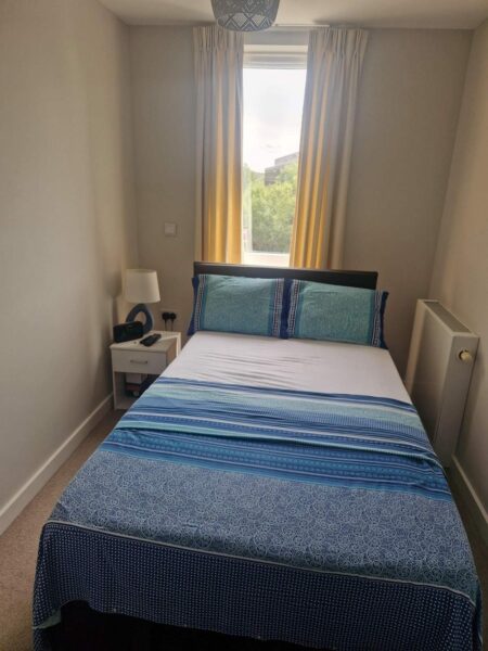 Made double bed with blue bedding in a bright bedroom