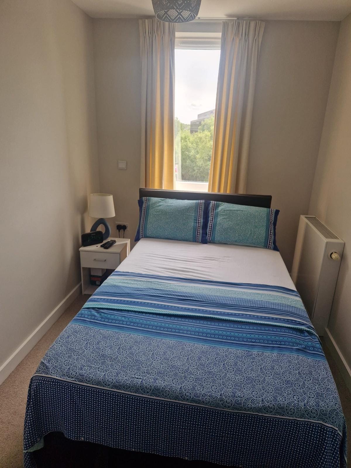 Made double bed with blue bedding in a bright bedroom