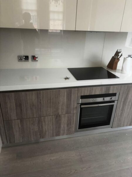 Kitchen with white gloss wall units, a black hob and a built-in oven