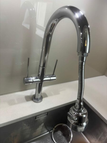 Chrome kitchen tap over a stainless steel sink