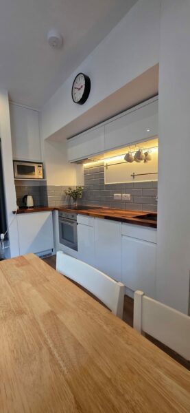 Kitchen with a wooden worktop and a wall clock