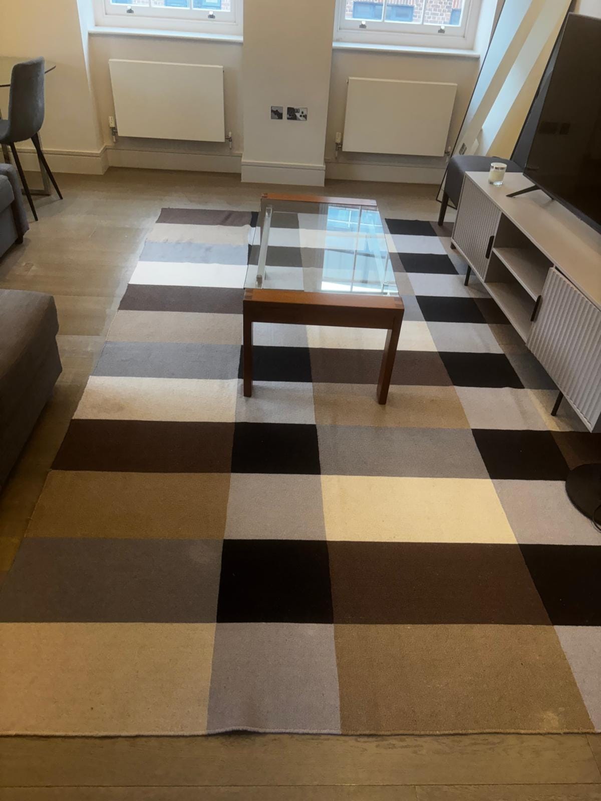 Living room with a checked rug and a glass coffee table