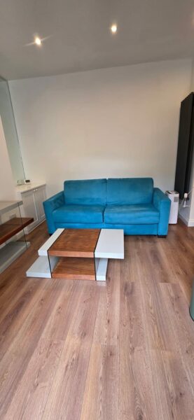 Living room with a blue sofa and a wooden floor
