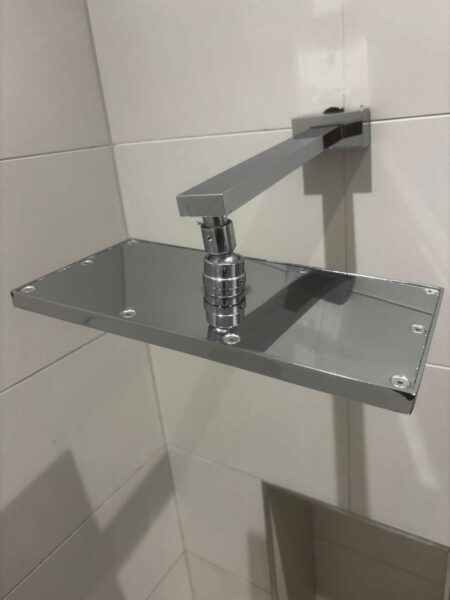 Square chrome shower head on a tiled wall