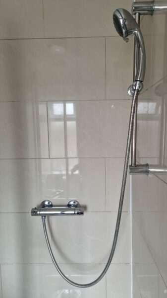Chrome shower on a white tiled wall